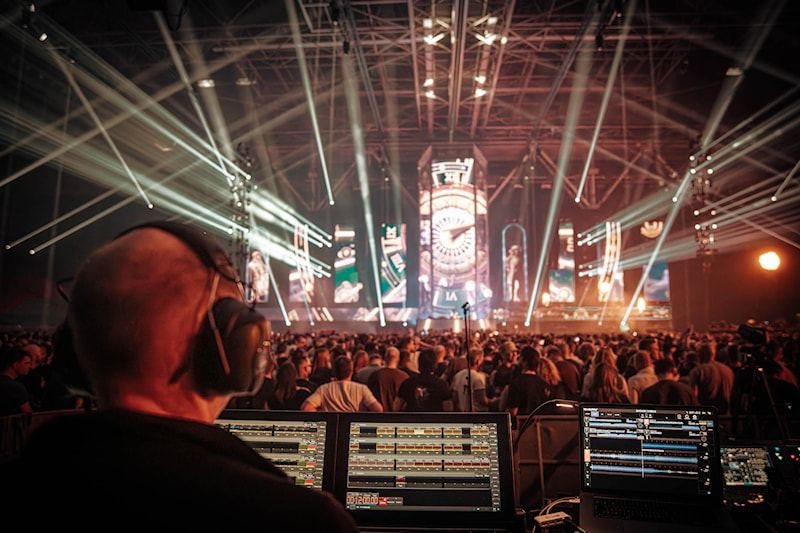 Showoperator aan de regietafel, met lasers boven het publiek