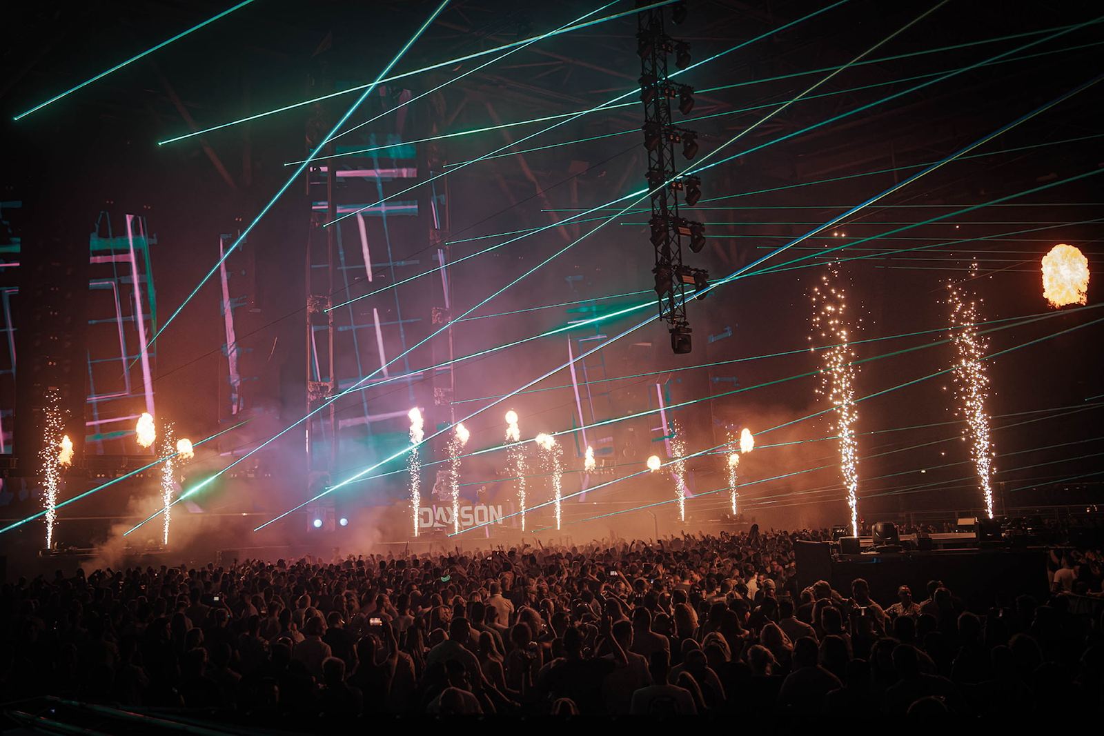 Lasers en vonkenfonteinen boven een festivalpubliek
