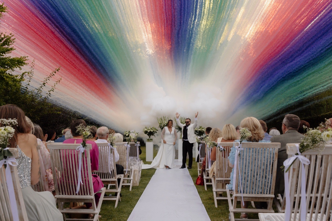 Coloured smoke over the aisle at an outdoor wedding ceremony